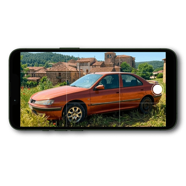 smartphone in funzione di fotocamera mentre inquadra un'auto abbandonata in un terreno